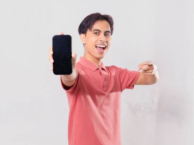 Neşeli Asyalı genç adam boş bir cep telefonu ekranına işaret ediyor.