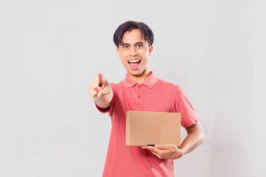 Neşeli Asyalı adam, elinde karton bir kutu ile dikilip dış dünya dağıtım konsepti için izole edilmiş bir şekilde bekliyor..