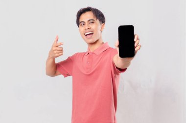 Neşeli Asyalı genç adam boş bir cep telefonu ekranına işaret ediyor.