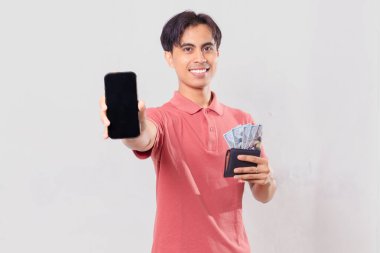 Gülümseyen Asyalı adam içi para dolu cüzdanı tutarken boş cep telefonu ekranı görüntüsü çiziyor.