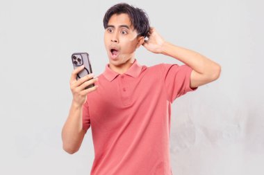 Genç adam akıllı telefon kullanırken şaşırmış görünüyor.