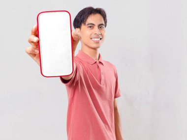 Gülümseyen kendine güvenen genç Asyalı adam boş akıllı telefon ekran modeli gösteriyor dijital mobil uygulama promosyonu için sade arka planda izole edilmiş..
