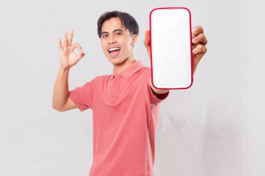 Dost canlısı genç Asyalı müşteri boş akıllı telefon ekran maketi gösteriyor ve uygulama önerisi için arka planda izole edilmiş ok işareti veriyor.