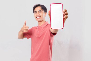 Dost canlısı genç Asyalı müşteri boş akıllı telefon ekran modeli gösteriyor ve hizmet memnuniyeti için arka planda izole edilmiş baş parmak hareketi yapıyor..