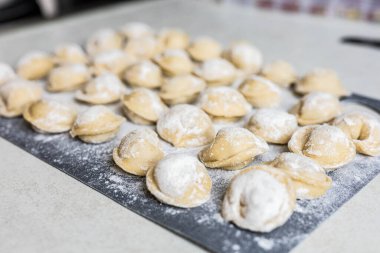 Mutfaktaki un ağacından yapılmış tahtanın üzerine yerleştirilmiş çiğ hamur tatlısı. Kaynatmadan önce geleneksel pişirme işlemi. Pişmemiş pelmeni 'ye yakın çekim. Yüksek kalite fotoğraf