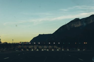 İtalya, 6 Eylül 2025, İtalyan otoyolu üzerinde birden fazla şerit ve araçla geçen bir tren istasyonu. Arka planda dağ manzarası var. İtalya 'da ücretli yol altyapısı. Yüksek kalite fotoğraf