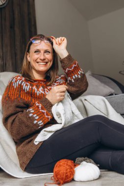 Gülümseyen kadın evde örgü örmekten, rahat bir kazak üzerinde çalışmaktan hoşlanıyor. Onun hobisi yavaş bir yaşam tarzı ve iç huzurunu yansıtan farkındalık, rahatlık ve neşe getirir. Yüksek kalite fotoğraf