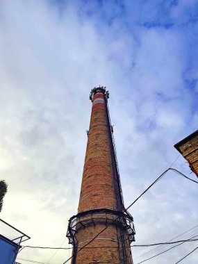 Endüstriyel baca arka planda bulutlu gökyüzünden görünüyor. Kentsel bozulma ve endüstriyel mimari kavramı.