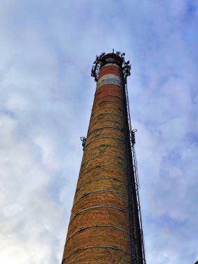 Endüstriyel baca arka planda bulutlu gökyüzünden görünüyor. Kentsel bozulma ve endüstriyel mimari kavramı.