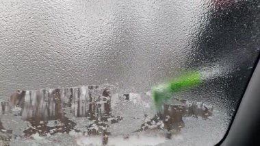 Fırçalı adam arabanın ön camını buz ve buzdan temizliyor. Kışın, camdaki buz gibi desen. Soğuk bir sabah, donmuş nakliye aracı, yolculuğa hazırlanıyor. Temizlik