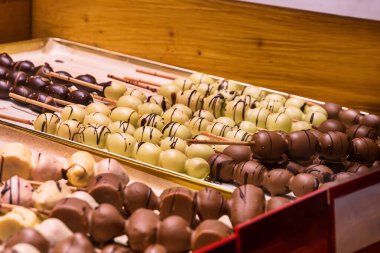 Çikolata kaplı meyveli şişe yakın çekim. Sıralar dolusu çikolata soslu elma, muz çileği şişleri Noel pazarında sıraya dizilmiş. Schokofrucht - Geleneksel Alman bayramı