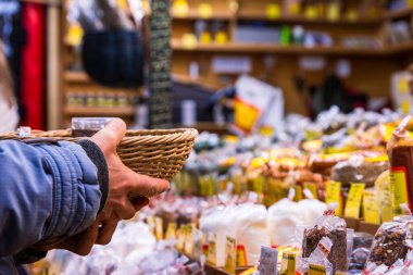 Wuerzburg, Almanya, 22 Aralık 2024. Bir Alman noel tezgahında çeşitli paketlenmiş baharatlarla dolu tezgahta dokuma sepetleri düzenleyen bir satıcı..
