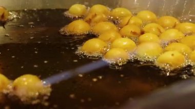 Şenlikli bir kış pazarında kızartma makinesinde cızırdayan hamur topları kızartma yağının dokusunu, pişirme sürecini ve sokak yemeği hazırlama atmosferini gösteriyor.