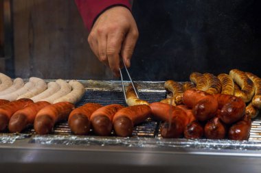 Kırmızı örgü süveter giyen satıcılar yoğun bir Noel pazarında çeşitli şekerleri desenli bir kese kağıdına dolduruyorlar.