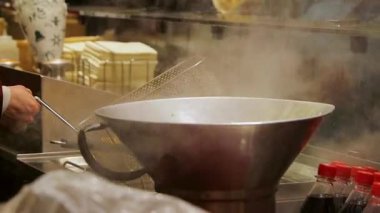 Bir metal tencere ve fritöz tezgahın üzerine yerleştirilmiş şişeler ve ambalaj malzemeleriyle birlikte bir Noel marketinin açık mutfağına buhar salıyor..