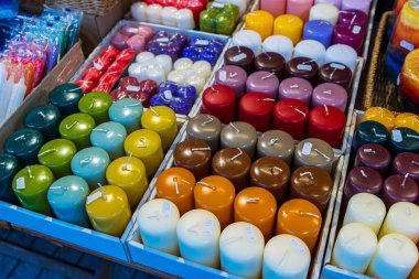 Şenlikli bir pazarda sıra sıra dizilmiş çeşitli renkli mumların sergilenmesi. Fiyat etiketli renkli mumlar panayırda