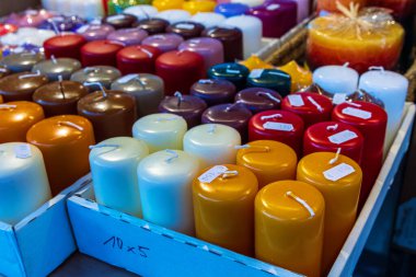 Şenlikli bir pazarda sıra sıra dizilmiş çeşitli renkli mumların sergilenmesi. Fiyat etiketli renkli mumlar panayırda