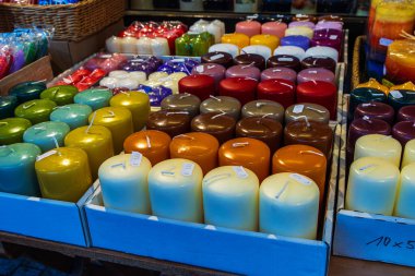 Şenlikli bir pazarda sıra sıra dizilmiş çeşitli renkli mumların sergilenmesi. Fiyat etiketli renkli mumlar panayırda