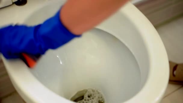 Дівчина в блакитних рукавичках миє ванну кімнату, прибираючи туалет. Прибиральниця як прибиральниця в туалеті. Чистити туалет для чистоти та гігієни. прибирання туалету. Концепція клінінгової служби — стокове відео