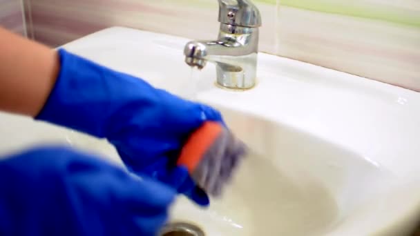 Girl in blue gloves washes the sink, cleaning the bathroom. Housekeeper as a cleaner at the sink. Brush up Toilet for cleanliness and hygiene. cleaning the sink. Cleaning service concept — Stock Video