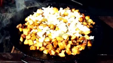 Patatesin üstüne çiğ soğan. Ateşin üzerinde domuz yağıyla kızarmış patates pişirmek. Doğada ızgara patates yemeği.