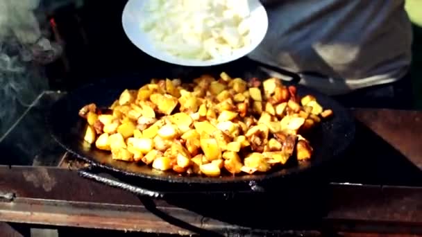 La niña se queda dormida cebolla cruda en papas con tocino. Cocinar papas fritas con manteca de cerdo sobre el fuego. Plato de papa a la parrilla en la naturaleza. — Vídeos de Stock