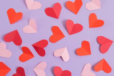 Sevgililer Günü geçmişi. Pastel mor arka planda pembe ve kırmızı kalpler. Sevgililer Günü konsepti. Kartpostalların planı ve tebrikler. Düz konum, üst görünüm, kopyalama alanı