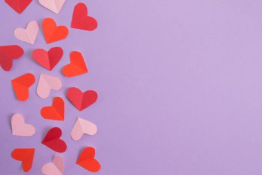Sevgililer Günü geçmişi. Pastel mor arka planda pembe ve kırmızı kalpler. Sevgililer Günü konsepti. Kartpostalların planı ve tebrikler. Düz konum, üst görünüm, kopyalama alanı