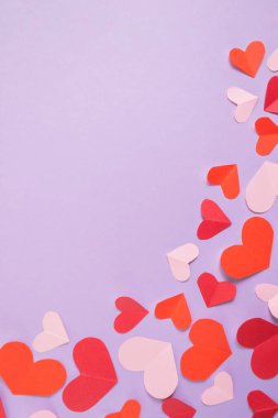 Sevgililer Günü geçmişi. Pastel mor arka planda pembe ve kırmızı kalpler. Sevgililer Günü konsepti. Kartpostalların planı ve tebrikler. Düz konum, üst görünüm, kopyalama alanı