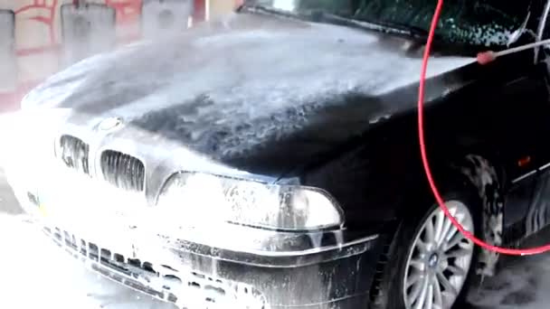 Augusztus, 2020, Vinnytsia: A folyamat a mosás egy BMW üzleti osztályú autó, öblíti a hab egy vízipisztoly. Az autószerviz és a mosógép koncepciója — Stock videók