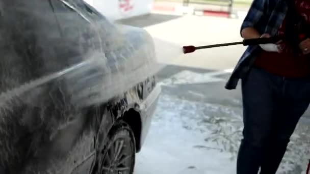 Srpen, 2020, Vinnytsia: Prací proces pro BMW kompletně pokrytý bílou pěnou a sprejem z vodní pistole. Pěnová aplikace na lesklý exteriér vozu. Koncepce automatického servisu a pračky