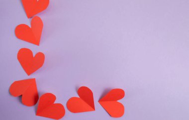 Sevgililer Günü geçmişi. Pastel mor arka planda pembe ve kırmızı kalpler. Sevgililer Günü konsepti. Kartpostalların planı ve tebrikler. Düz konum, üst görünüm, kopyalama alanı