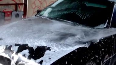 BMW birinci sınıf bir arabayı yıkama, su tabancasının köpüğünü durulama işlemi. Otomobil ve çamaşır makinesi kavramı