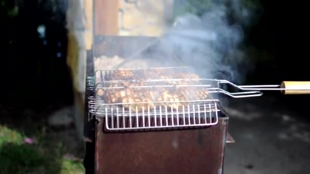 닭고기 고기는 넓은 공기중에서 그릴 위에서 튀겼습니다. 범인 이 불을 붙이고 있어요. 닭고기를 요리하고 볶는 일. 작은 카메라의 움직임, 선택적 인 초점. — 비디오