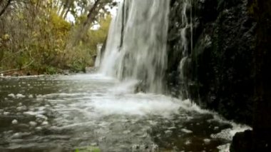 Bir dağ ormanında akan kristal berrak suyun videosunu kapat. Küçük su damlacıkları. Dağlardaki nehirden küçük bir şelale. Doğa ve ekoloji. Saf su..