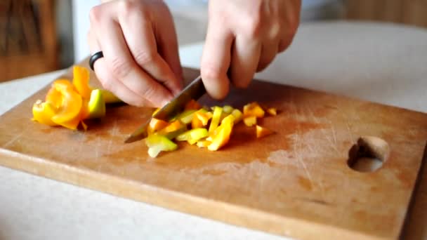 Szef kuchni kroi warzywa nożem. Kobieta kroi żółtą paprykę na kostkę na drewnianej desce do krojenia dużym ostrym nożem. Pojęcie gotowania w domu. — Wideo stockowe