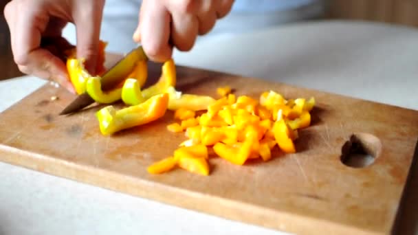 Donna taglia e taglia a dadini il peperone giallo su un tagliere di legno con un grosso coltello affilato. Concetto di cucina a casa. — Video Stock