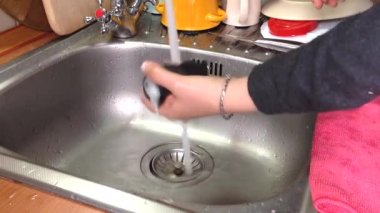 Kadınların elleri mutfak lavabosunu pislikten temizler. Bir kız havluya köpük temizleyici sürüyor ve lavaboyu yıkamaya başlıyor. Ev işleri işte. Mutfağı ve günlük hayatı temizleme kavramı.