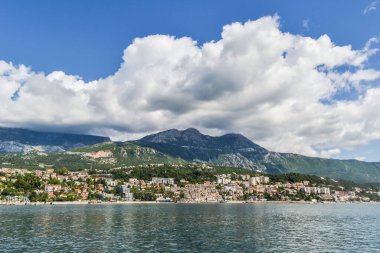 Deniz manzarası ve güzel şehir manzarası. Sahildeki dağların eteklerinde. Büyük bulutlarla aydınlık bir günde.