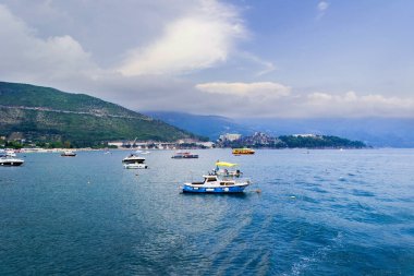 Budva, Karadağ, 16 Temmuz 2021: Deniz balıkçılığında motorlu tekneler. Budva şehrini bir yattan, arka planda bitki örtüsü olan bir dağ sırasından yakından çek. Karadağ kıyısı boyunca seyahat et..