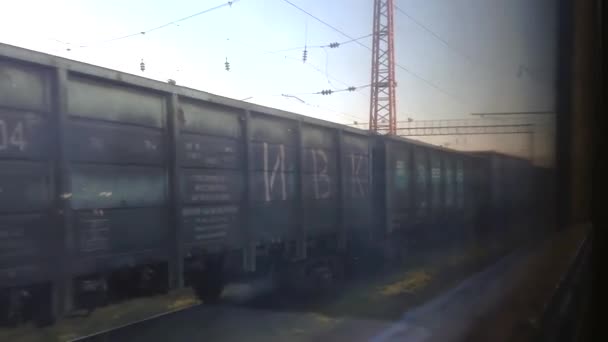 Winniza, Ukraine, 5. August 2021: Güterzug mit Diesellok auf der ukrainischen Eisenbahn, Blick vom Personenwagen auf den Bahnhof, Güterwagen verlassen den Bahnhof mit Fracht. — Stockvideo