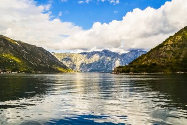 Karadağ 'ın Boka Kotorska Körfezi' ndeki güzel deniz, dağlar ve mavi gökyüzü manzarası. Yattan dağ manzarası.