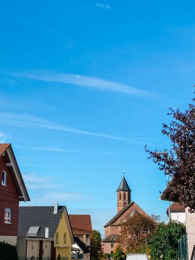 Canlı evler ve güneş ışığıyla yıkanmış güzel bir kilisenin olduğu pitoresk bir sokak manzarası.