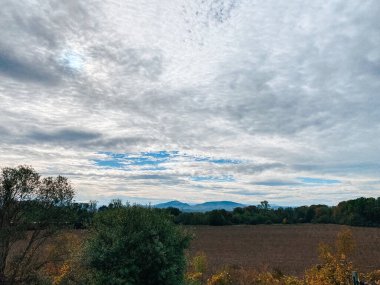 Açık arazilerin ve bulutlarla dolu gökyüzünün altındaki uzak tepelerin manzarası. Huzurlu doğa titreşimlerini yakalıyor.