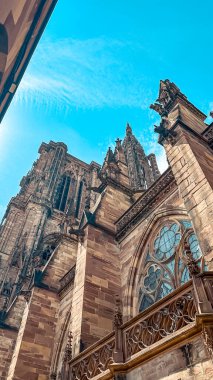 Gotik katedral çarpıcı mimari özellikler ve karmaşık taş işçiliği sergiliyor, açık mavi gökyüzüne doğru uzanarak, yapının ihtişamını ve tarihsel önemini vurguluyor.