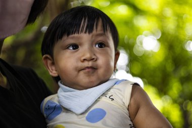 Küçük çocuk gecenin ışıklarıyla büyülenmiş ana kollarında büyülenmiş bir çocuk anne kollarından gece ışıklarına bakıyor karanlıkta parlayan gözler aile fotoğrafı için mükemmel ya da büyülü bir an gösterisi için mükemmel..