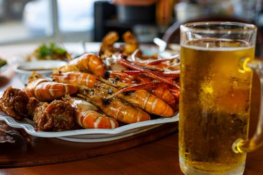 Izgara karides ve partide soğuk bira, canlı bir partide buzlu soğuk biranın yanında ızgara karidesin canlı bir fotoğrafı, deniz ürünleri kampanyası ya da bir belgesel için mükemmel..