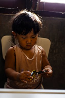 Toddler Pushes Toy Car, oyuncak arabayı iterken çekilmiş neşeli bir reklam fotoğrafı, eğlenceli hareketlere tutunan minik eller, eğlence kampanyası ya da çocuk hareketliliği belgeseli için mükemmel..