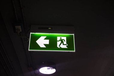 Acil durum ışığı için yeşil yangın çıkışı tabelası, parlayan yeşil yangın çıkışı tabelası, temel güvenlik işaretini ve acil durum rehberliğini yakalayan, güvenlik belgeseli ve endüstriyel için mükemmel bir fotoğraf..