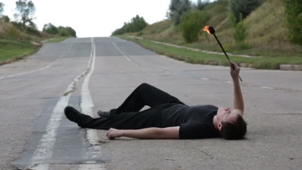 The fire eater, spitting fire, lying on the pavement — Stock Video